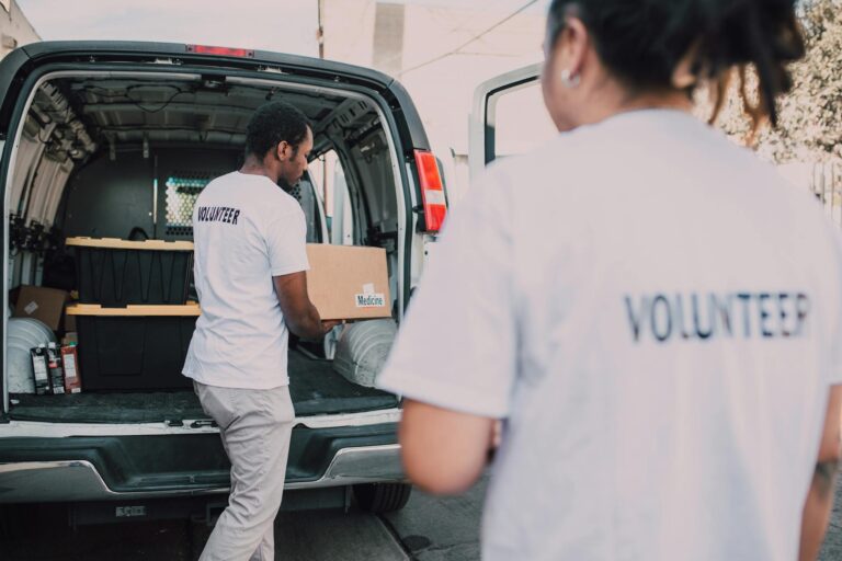 Volunteers loading medicine supplies into a van for donation and distribution.