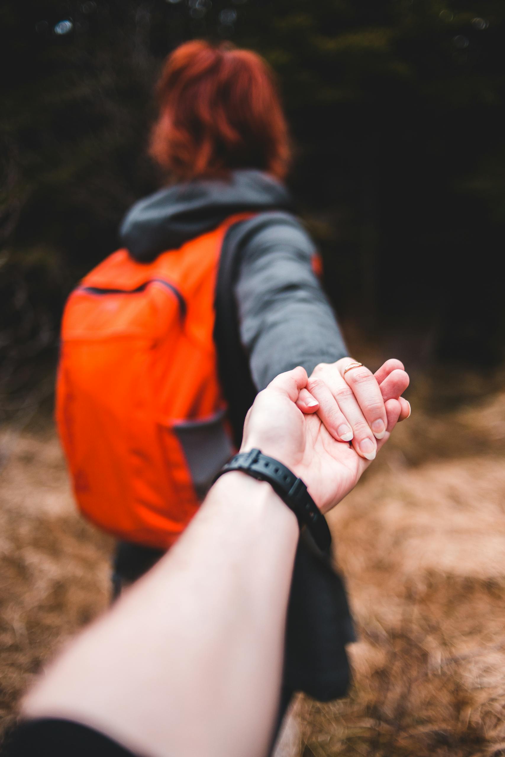 A couple holding hands while exploring an outdoor forest area.